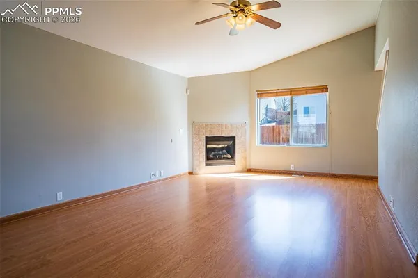a view of an empty room with a window and wooden floor