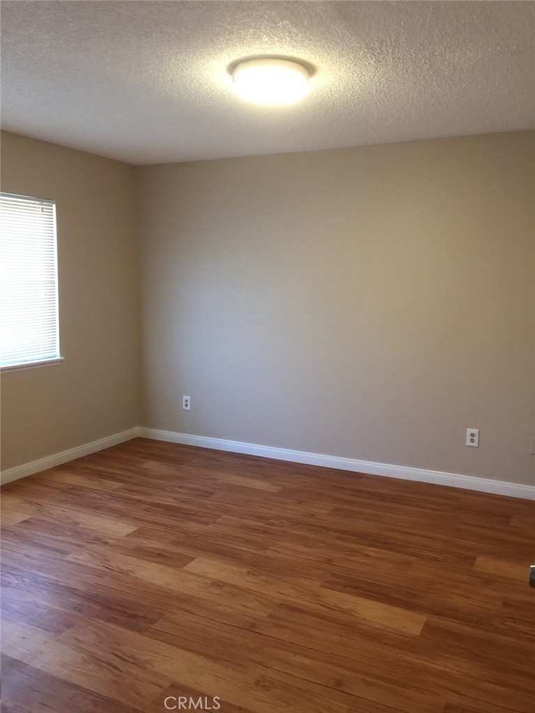 20955 Little Beaver Road, Unit 2 Apple Valley, CA 92308 - Photo 6 of 8 a view of an empty room with wooden floor and a window