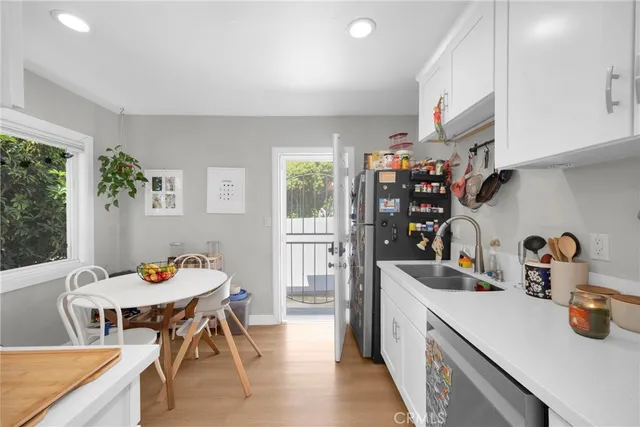 a kitchen with stainless steel appliances granite countertop a stove top oven a sink dishwasher and white cabinets with wooden floor