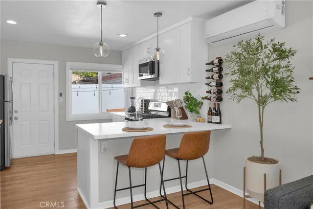 a kitchen with stainless steel appliances granite countertop a sink a stove a refrigerator white cabinets and wooden floor