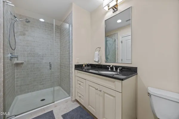 a bathroom with a granite countertop sink a toilet a mirror and shower