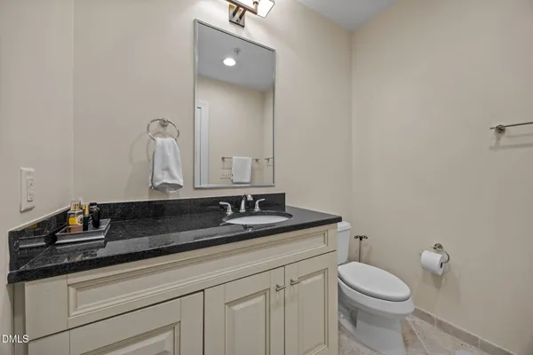 a bathroom with a granite countertop sink and a mirror with toilet