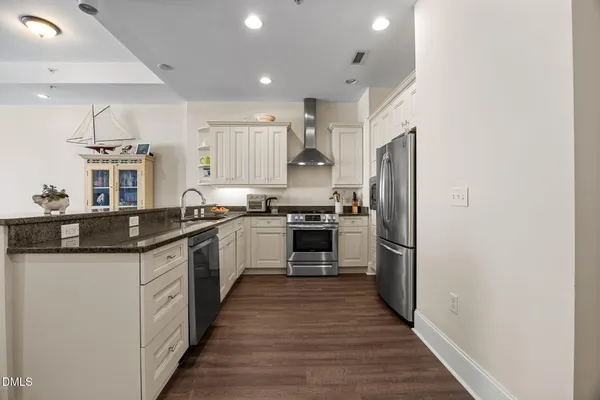 a kitchen with stainless steel appliances granite countertop a refrigerator a stove top oven a sink and dishwasher