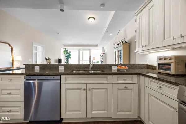 a kitchen with granite countertop white cabinets and stainless steel appliances