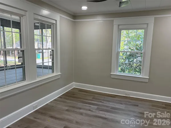 a view of empty room with wooden floor and fan