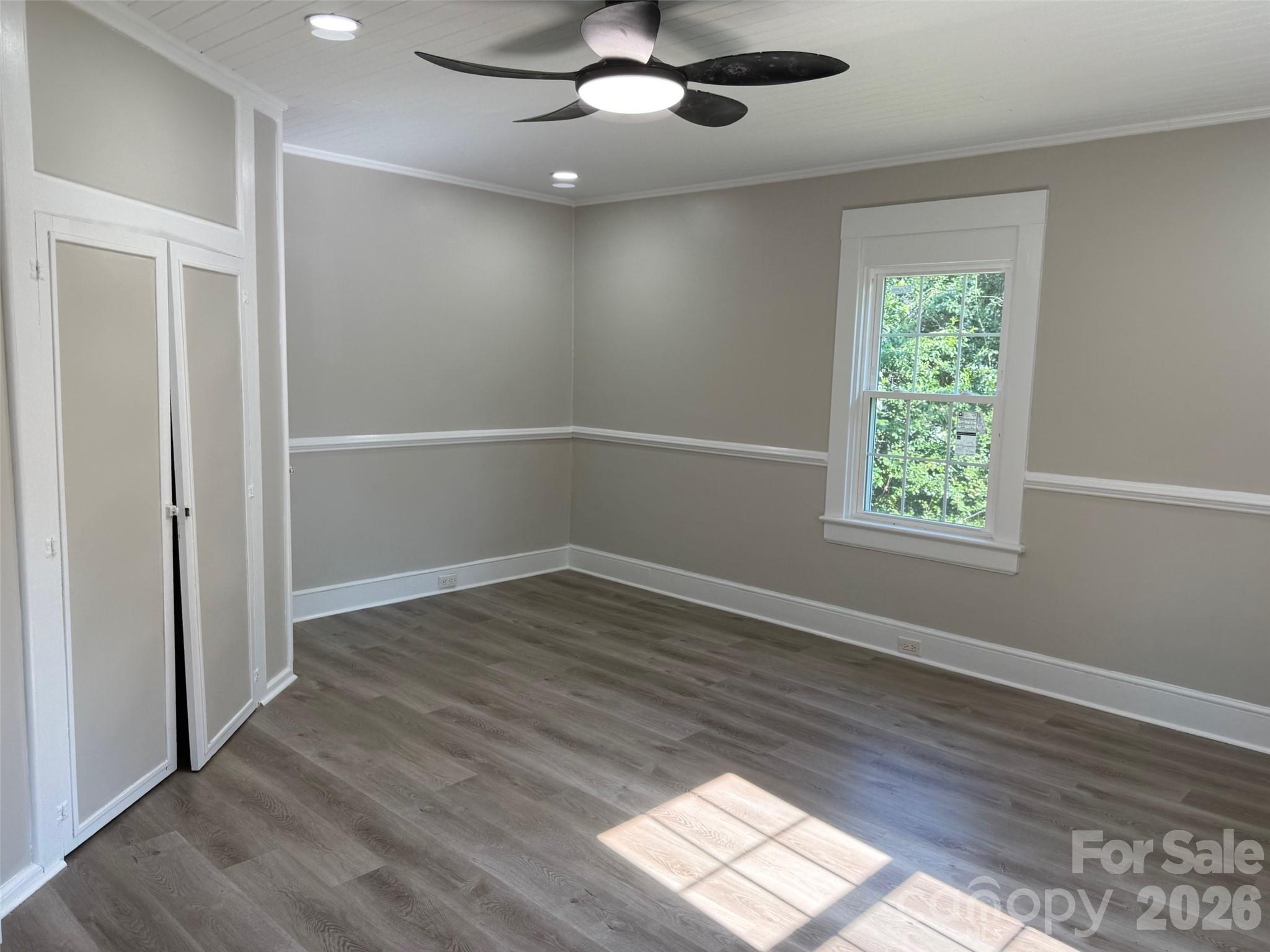 161 Seaboard Street Cheraw, SC 29520 - Photo 5 of 15 an empty room with wooden floor chandelier fan and windows