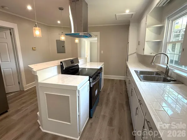 a kitchen with stainless steel appliances granite countertop a sink a stove and a wooden floors