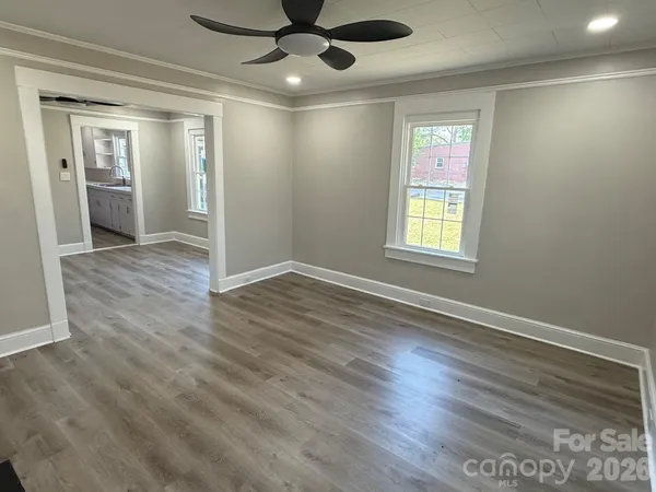 a view of an empty room with wooden floor and a window