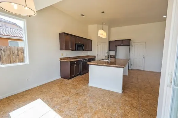 a large kitchen with cabinets a sink and a stove top oven with wooden floor