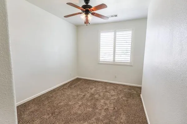 an empty room with windows and fan