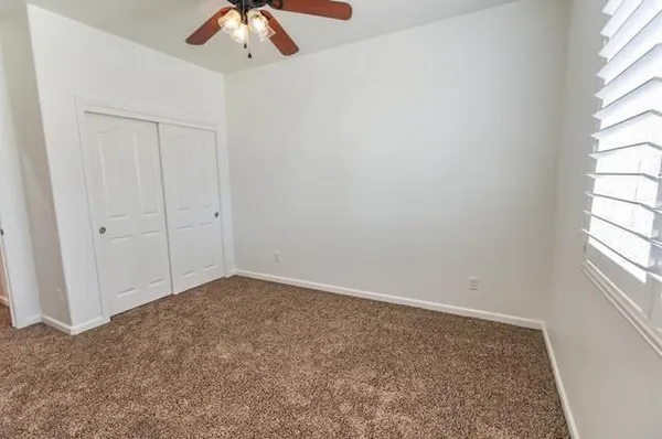 an empty room with a window and a chandelier fan