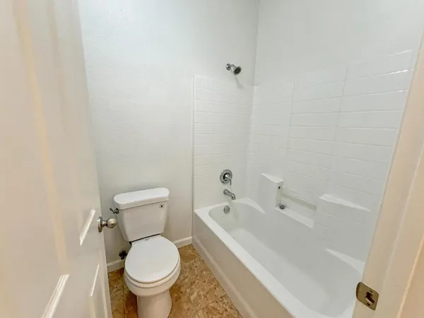 a white toilet sitting next to a bath tub