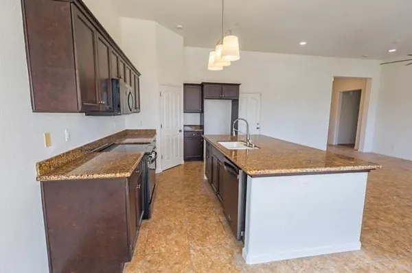 a kitchen with granite countertop a sink a counter top space and cabinets