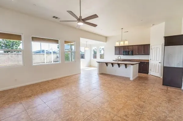 a large white kitchen with granite countertop a stove top oven a sink a counter space and cabinets