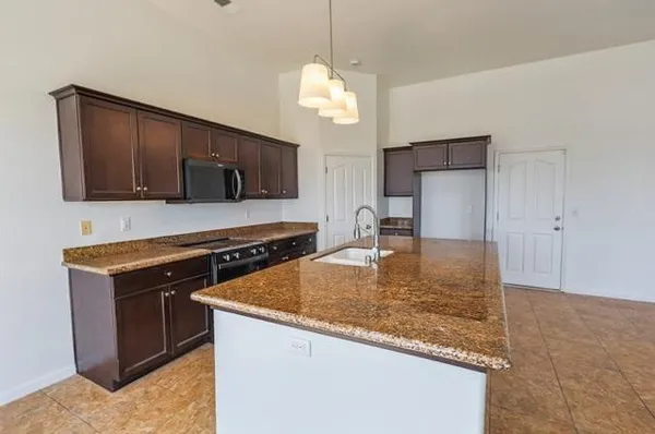 a kitchen with kitchen island granite countertop a sink a stove and oven