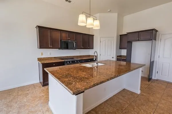 a kitchen with stainless steel appliances granite countertop a sink a microwave and a refrigerator