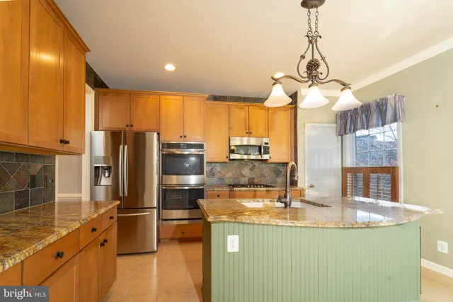 a kitchen with stainless steel appliances granite countertop a sink a stove and a refrigerator