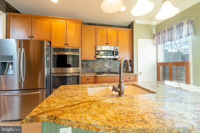 a large kitchen with kitchen island granite countertop a refrigerator oven stove top oven a sink and cabinets