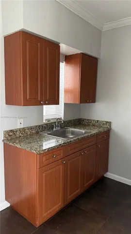 a kitchen with granite countertop a sink cabinets and wooden floor