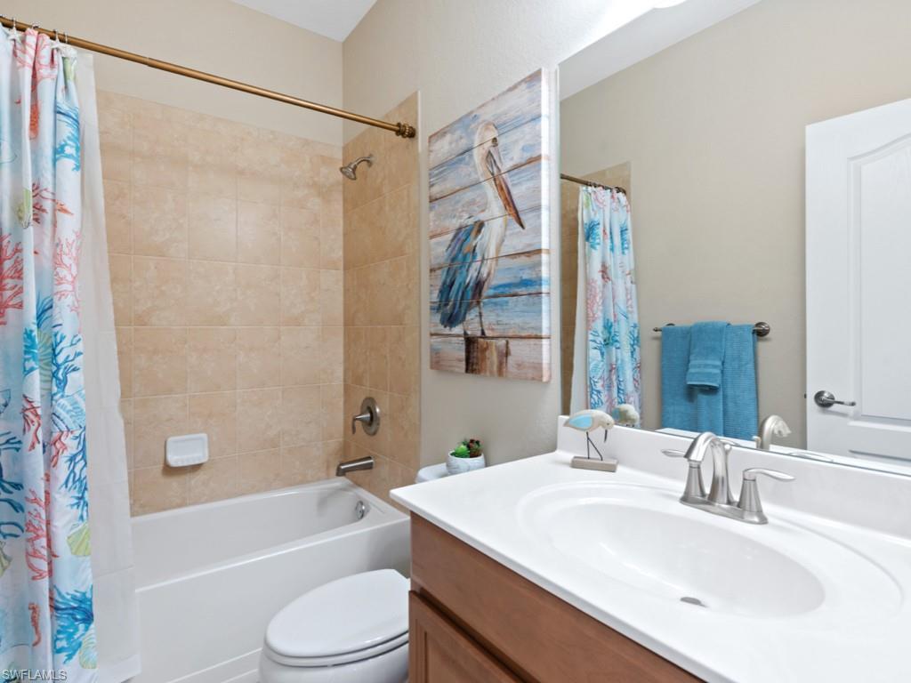 3913 Sapphire Way Naples, FL 34114 - Photo 16 of 32 a bathroom with a sink a toilet a mirror a bathtub and shower