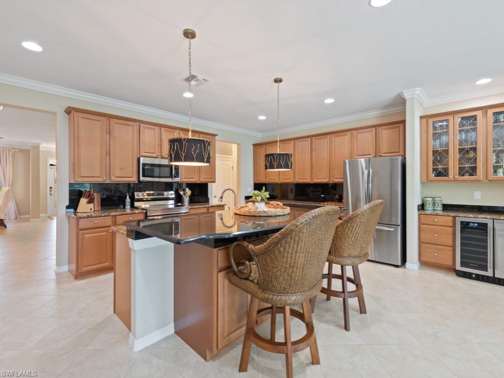 3913 Sapphire Way Naples, FL 34114 - Photo 7 of 32 a kitchen with stainless steel appliances granite countertop a stove top oven a refrigerator a sink a dining table and chairs