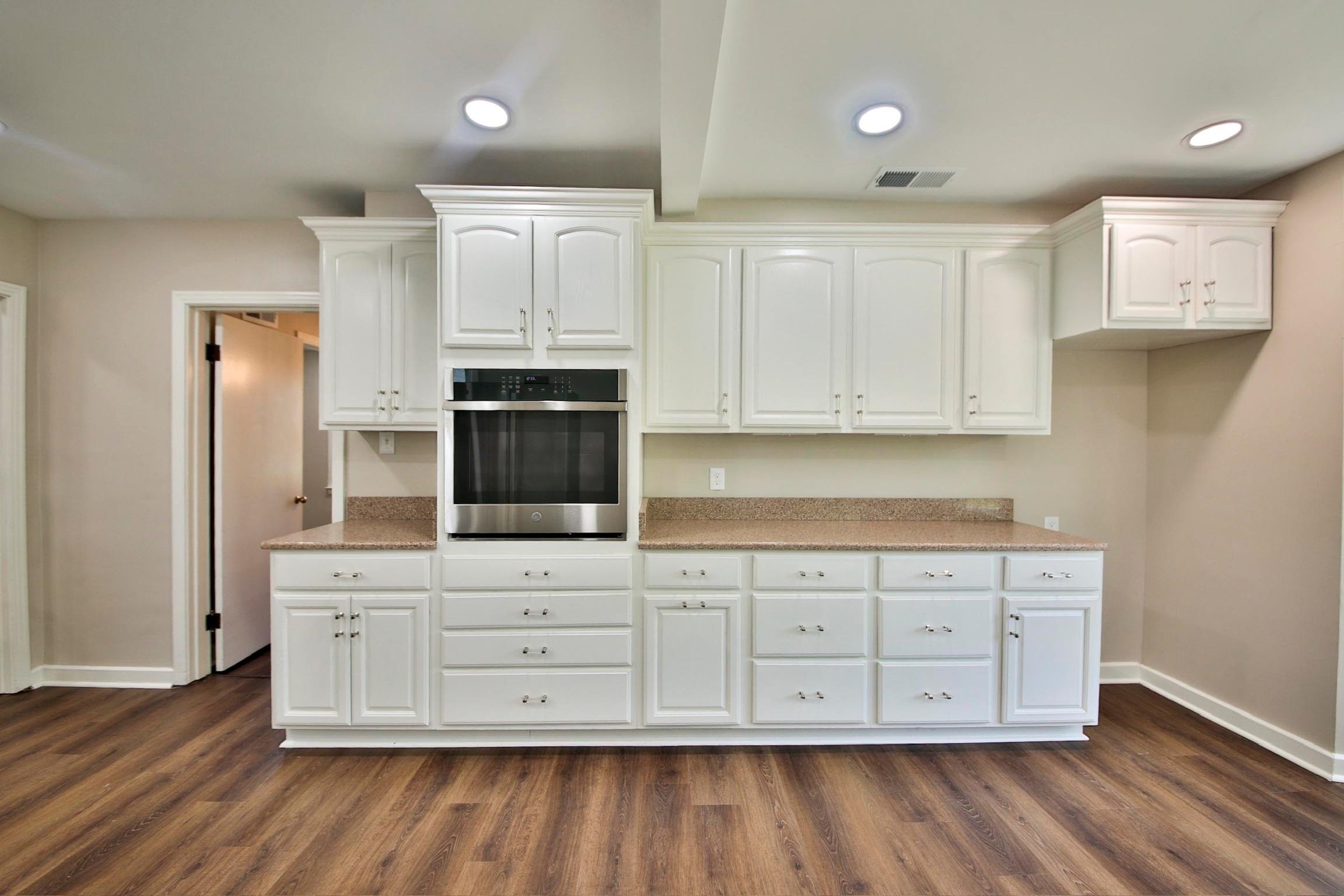 4869 Southern Road Memphis, TN 38117 - Photo 12 of 35 a kitchen with stainless steel appliances white cabinets and wooden floors