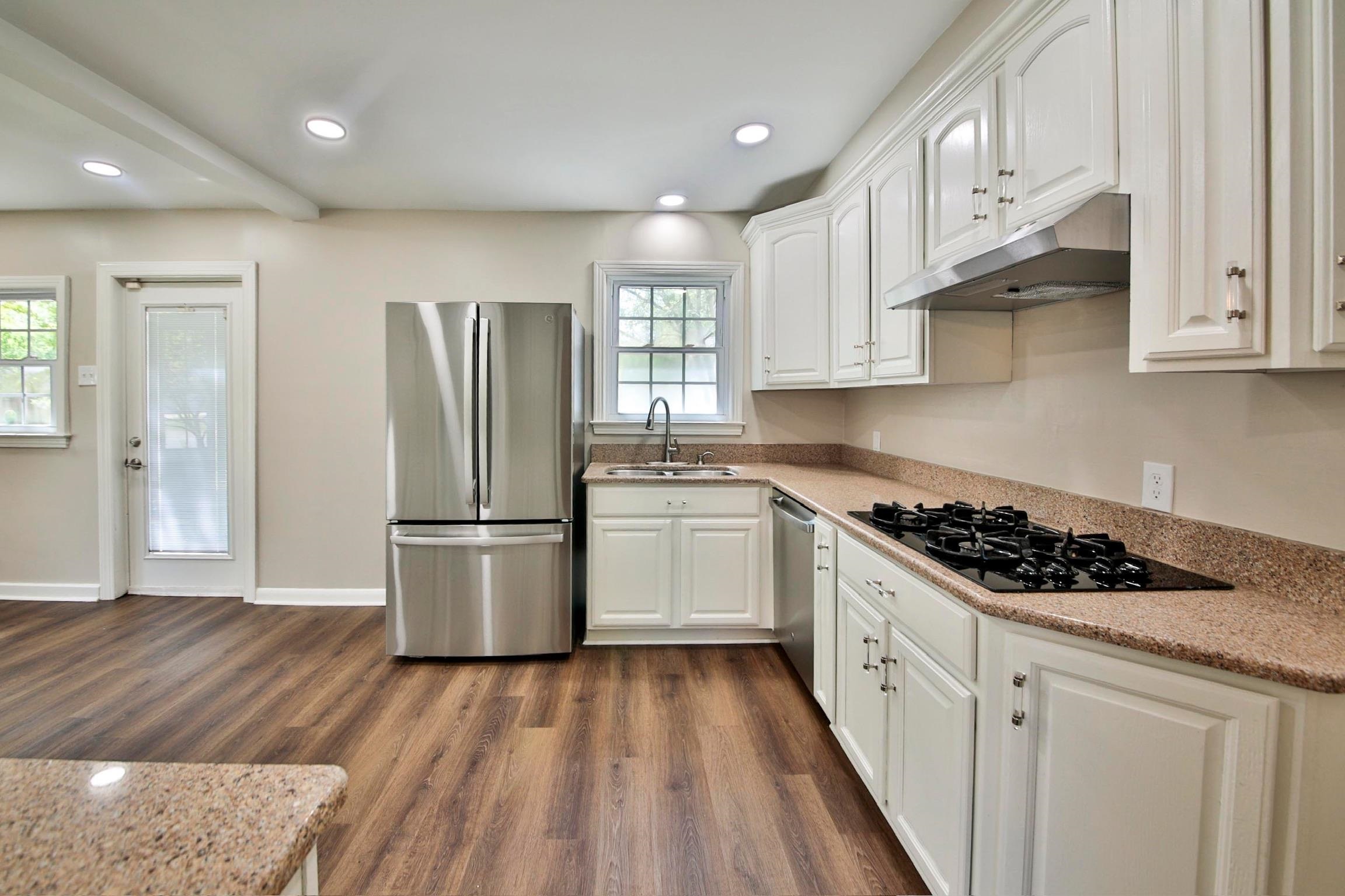 4869 Southern Road Memphis, TN 38117 - Photo 9 of 35 a kitchen with stainless steel appliances a refrigerator a sink dishwasher a stove and white cabinets with wooden floor