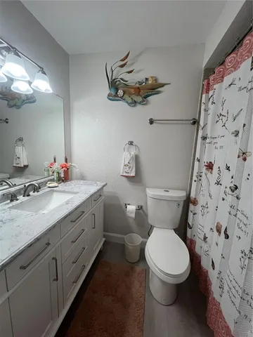 a bathroom with a granite countertop toilet sink and mirror