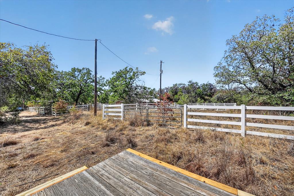 1623 3 Skillet Road Springtown, TX 76082 - Photo 37 of 40 Fenced perimeter with multiple gates, mature trees, and a clear sky backdrop