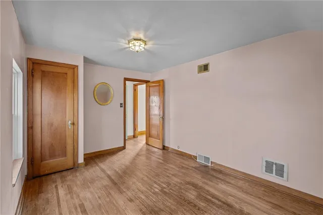 a view of an empty room with wooden floor and closet