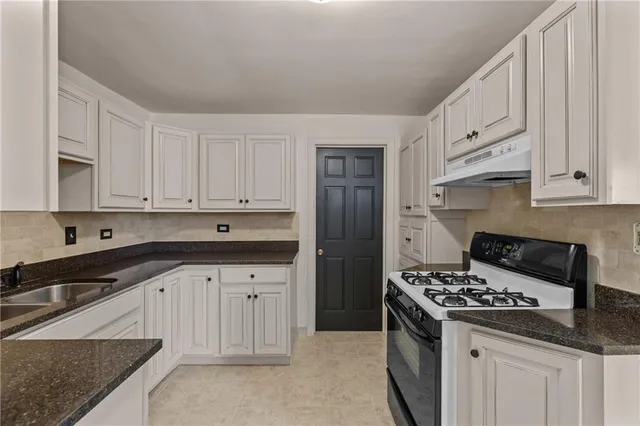 a kitchen with granite countertop white cabinets and stainless steel appliances