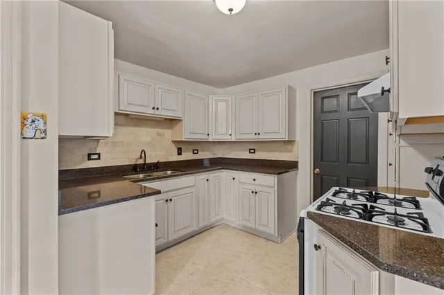 a kitchen with granite countertop a sink stove and refrigerator