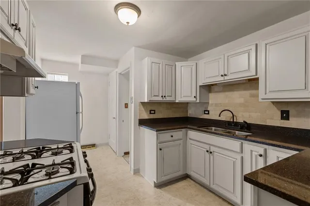 a kitchen with granite countertop a sink stove and refrigerator