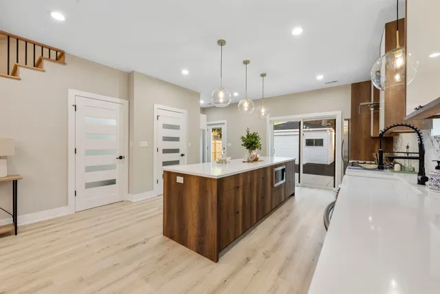 a large kitchen with kitchen island wooden floor a center island and stainless steel appliances