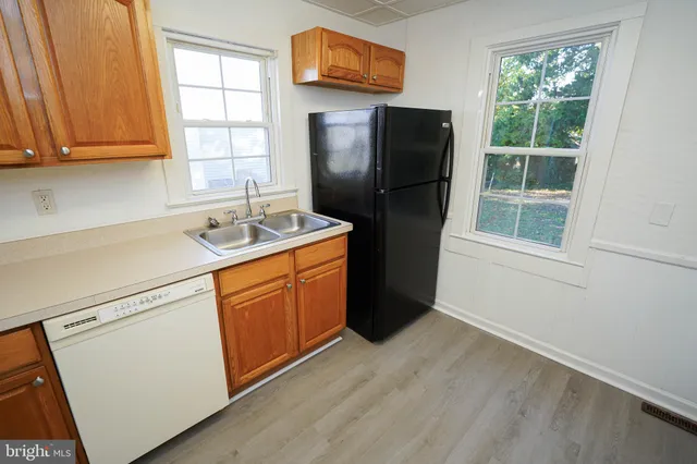 a kitchen with stainless steel appliances a refrigerator sink and wooden floor
