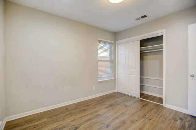 a view of an empty room with wooden floor and closet