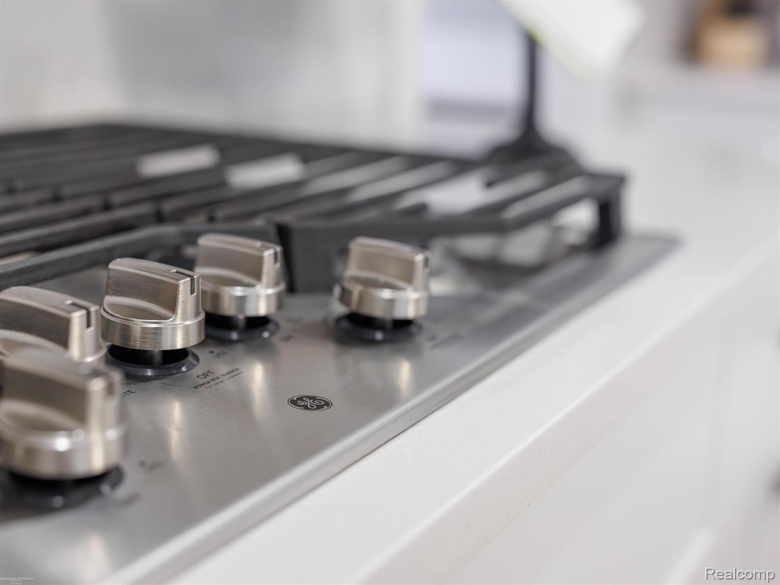 47705 Card Road Macomb, MI 48044 - Photo 14 of 53 Stainless steel gas cooktop with brushed metal control knobs, integrated into a white countertop