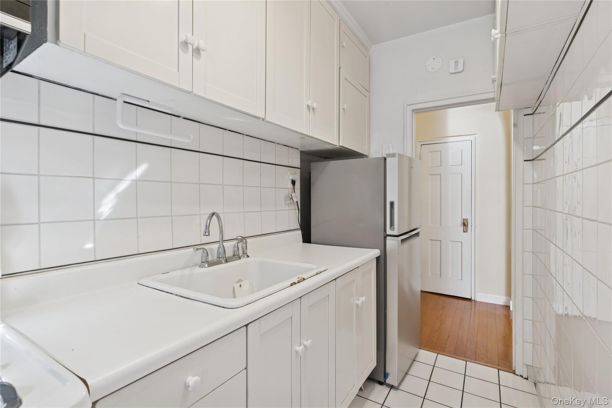 110-31 73rd Road, Unit 5N Queens, NY 11375 - Photo 7 of 13 Kitchen featuring white cabinets, light countertops, freestanding refrigerator, and light tile patterned floors