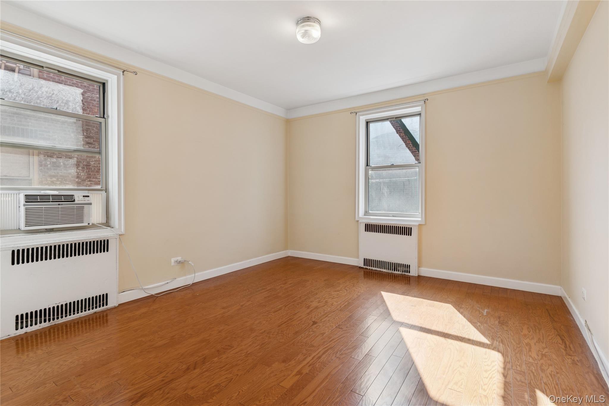 110-31 73rd Road, Unit 5N Queens, NY 11375 - Photo 8 of 13 Unfurnished room with radiator heating unit, light wood finished floors, cooling unit, and ornamental molding