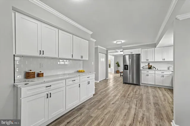 a large white kitchen with stainless steel appliances granite countertop a stove a sink and white cabinets