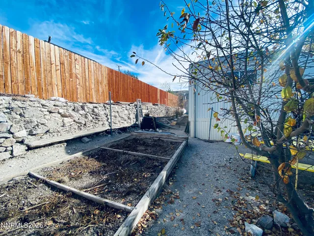 a view of a backyard with wooden fence and large trees