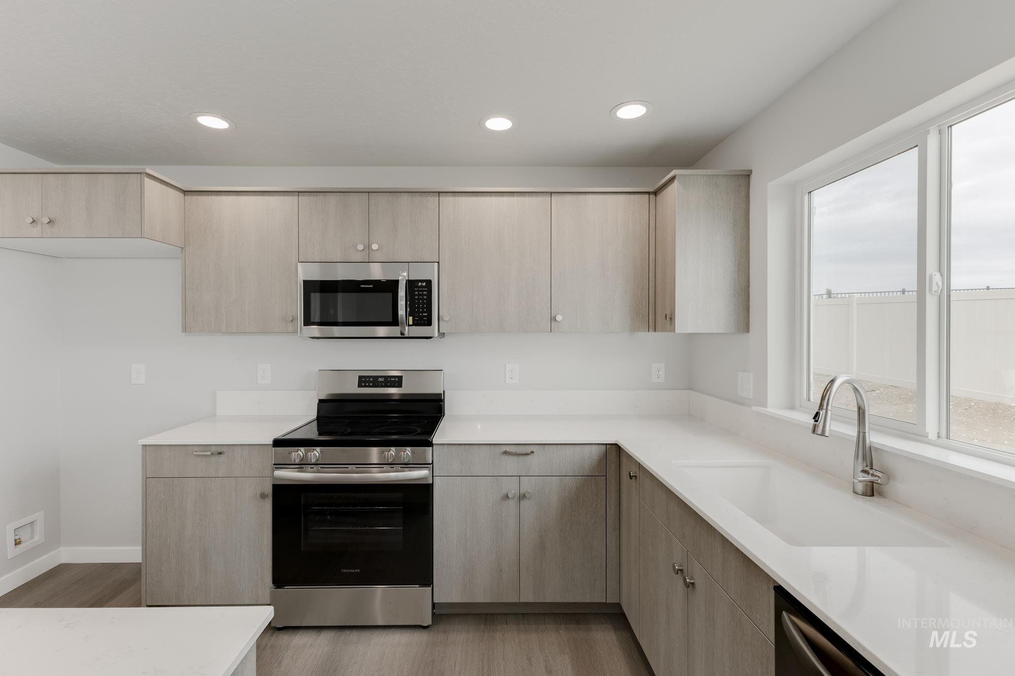 1602 Long Pond Street Middleton, ID 83644 - Photo 4 of 20 Kitchen with appliances with stainless steel finishes, light brown cabinets, recessed lighting, light wood-style flooring, and light stone countertops