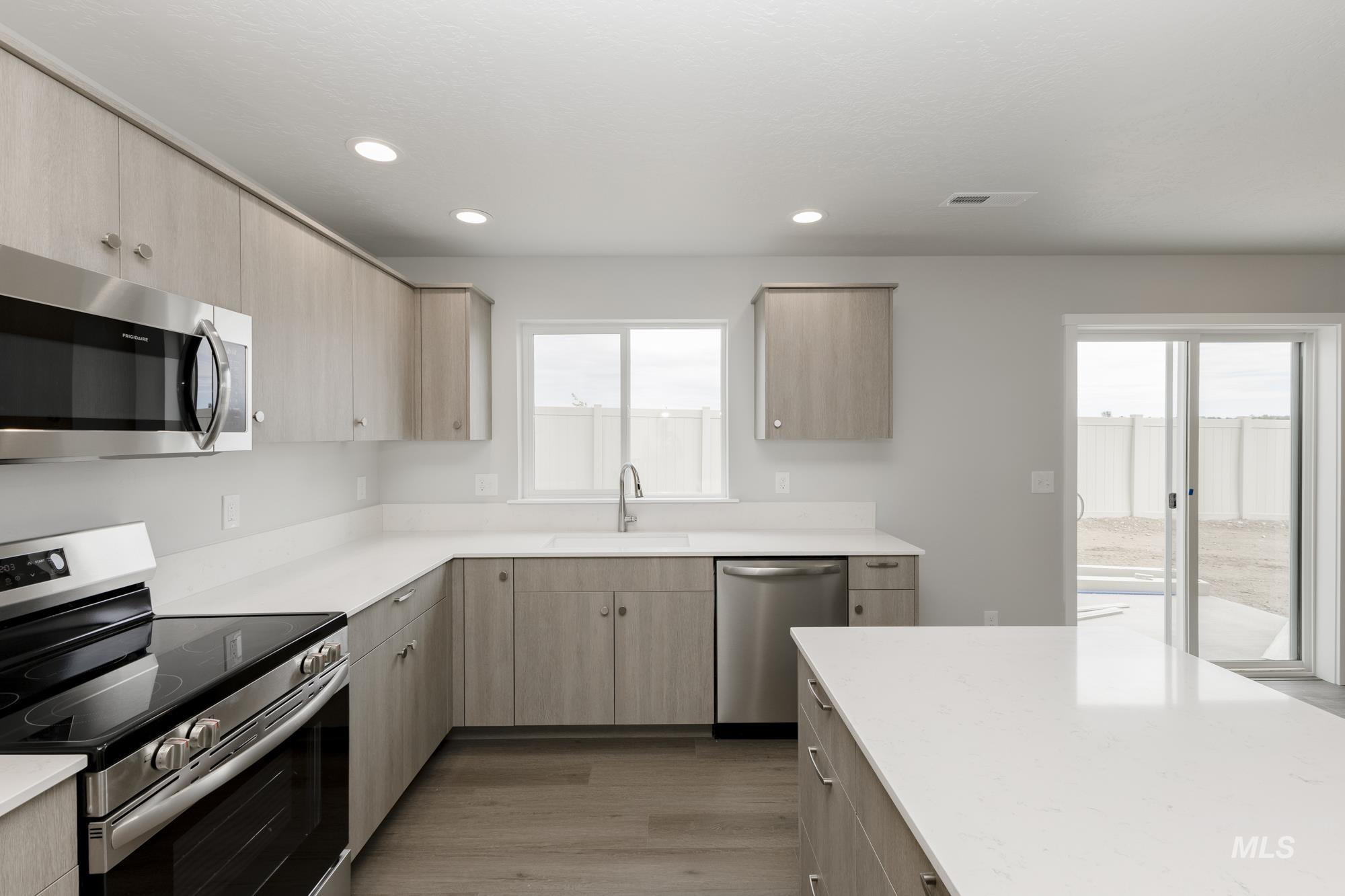 1602 Long Pond Street Middleton, ID 83644 - Photo 5 of 20 Kitchen featuring stainless steel appliances, light brown cabinetry, light wood-style floors, recessed lighting, and light stone countertops