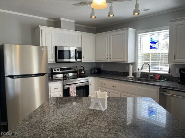 a kitchen with stainless steel appliances granite countertop a refrigerator a stove a sink and a microwave