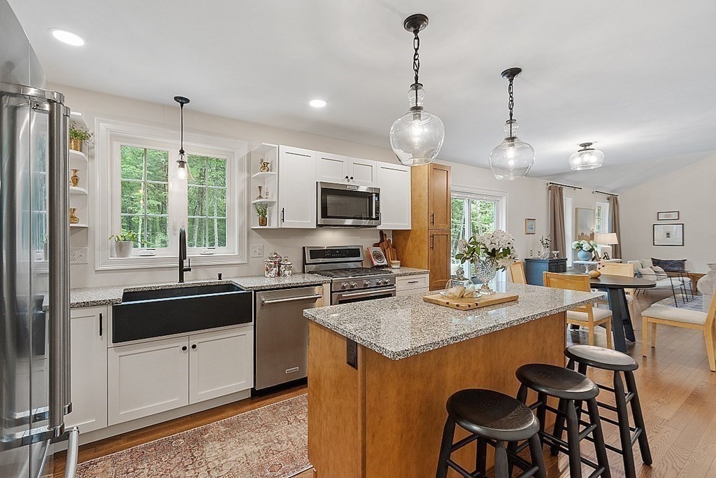 83 Russell Hill Road Brookline, NH 03033 - Photo 6 of 42 a kitchen with stainless steel appliances granite countertop a stove a sink a microwave a dining table and chairs