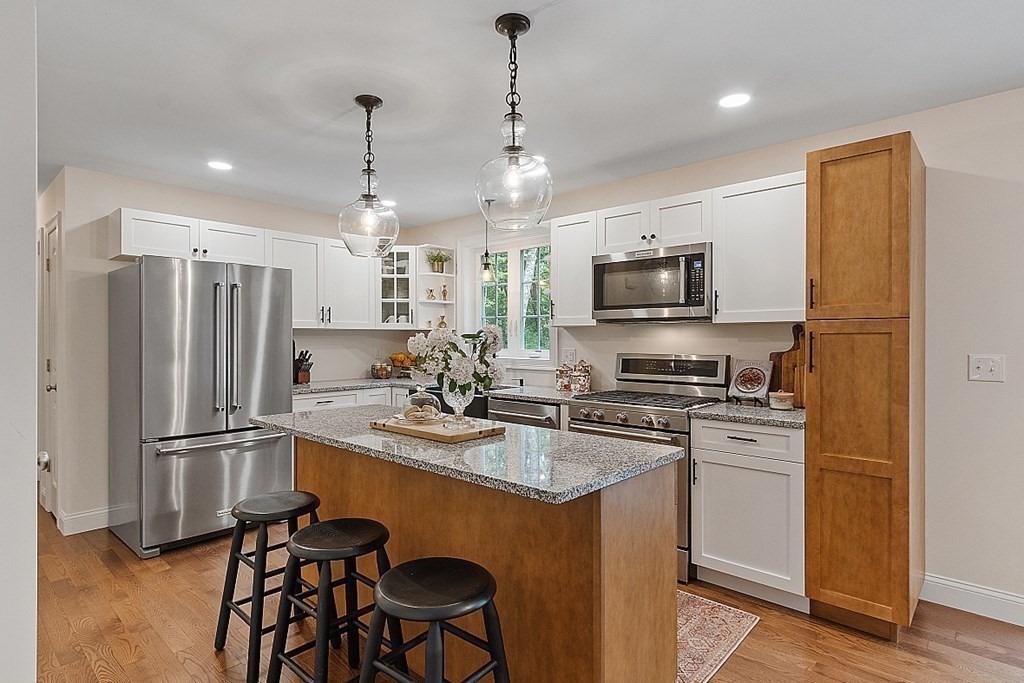 83 Russell Hill Road Brookline, NH 03033 - Photo 8 of 42 a kitchen with stainless steel appliances granite countertop a refrigerator a stove a microwave oven a sink with island chairs and wooden floor