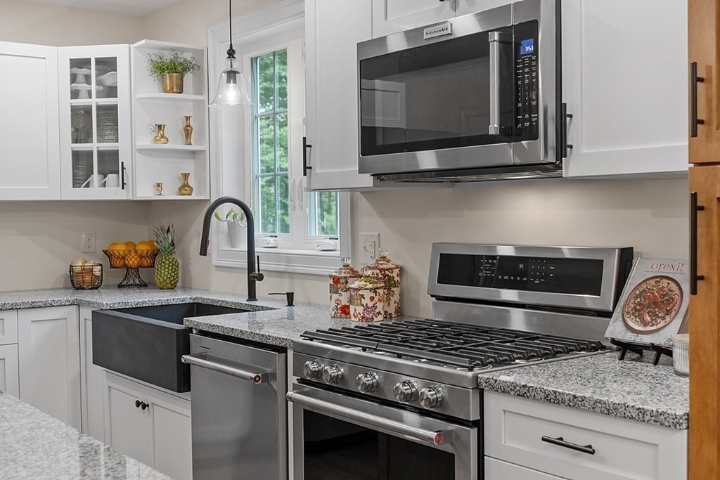 83 Russell Hill Road Brookline, NH 03033 - Photo 9 of 42 a kitchen with granite countertop a stove and a wooden floor
