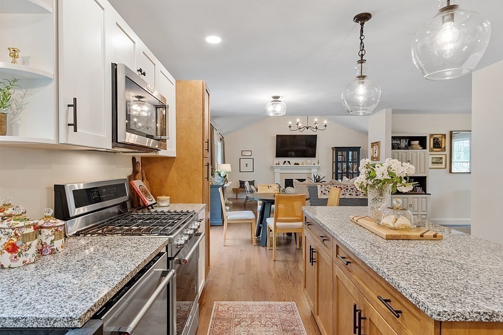 83 Russell Hill Road Brookline, NH 03033 - Photo 10 of 42 a kitchen with stainless steel appliances granite countertop a stove top oven a sink a dining table and chairs with wooden floor
