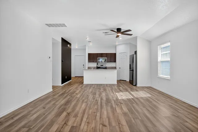 a view of a kitchen with wooden floor and a ceiling fan