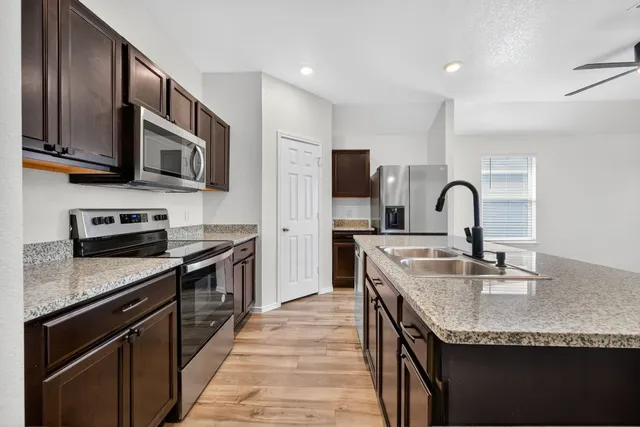 a kitchen with stainless steel appliances granite countertop a sink stove top oven and refrigerator
